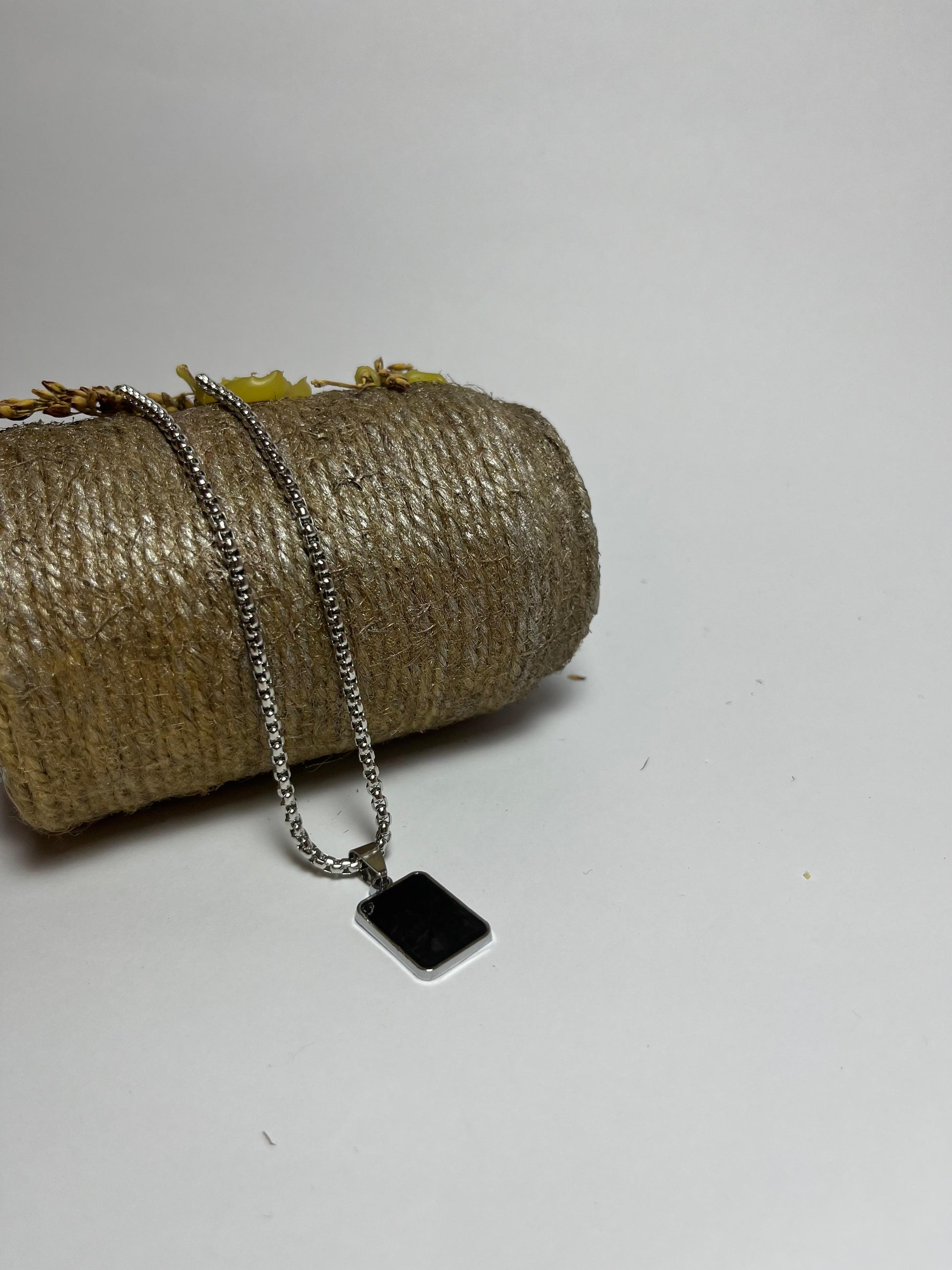 Necklace with a black square pendant on a textured surface