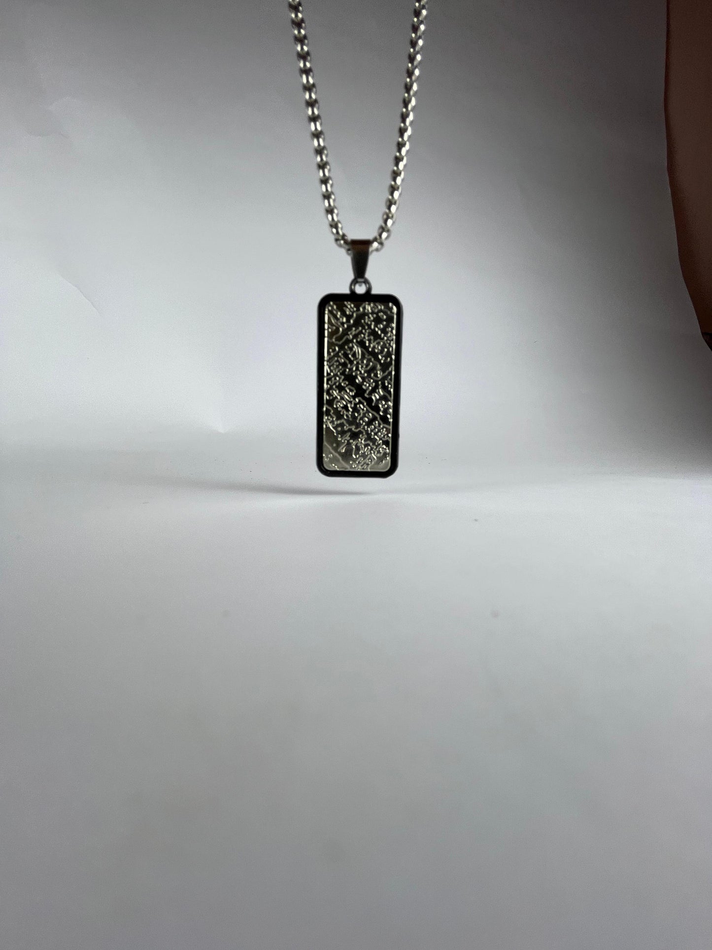 Rectangular pendant necklace on a chain against a plain background