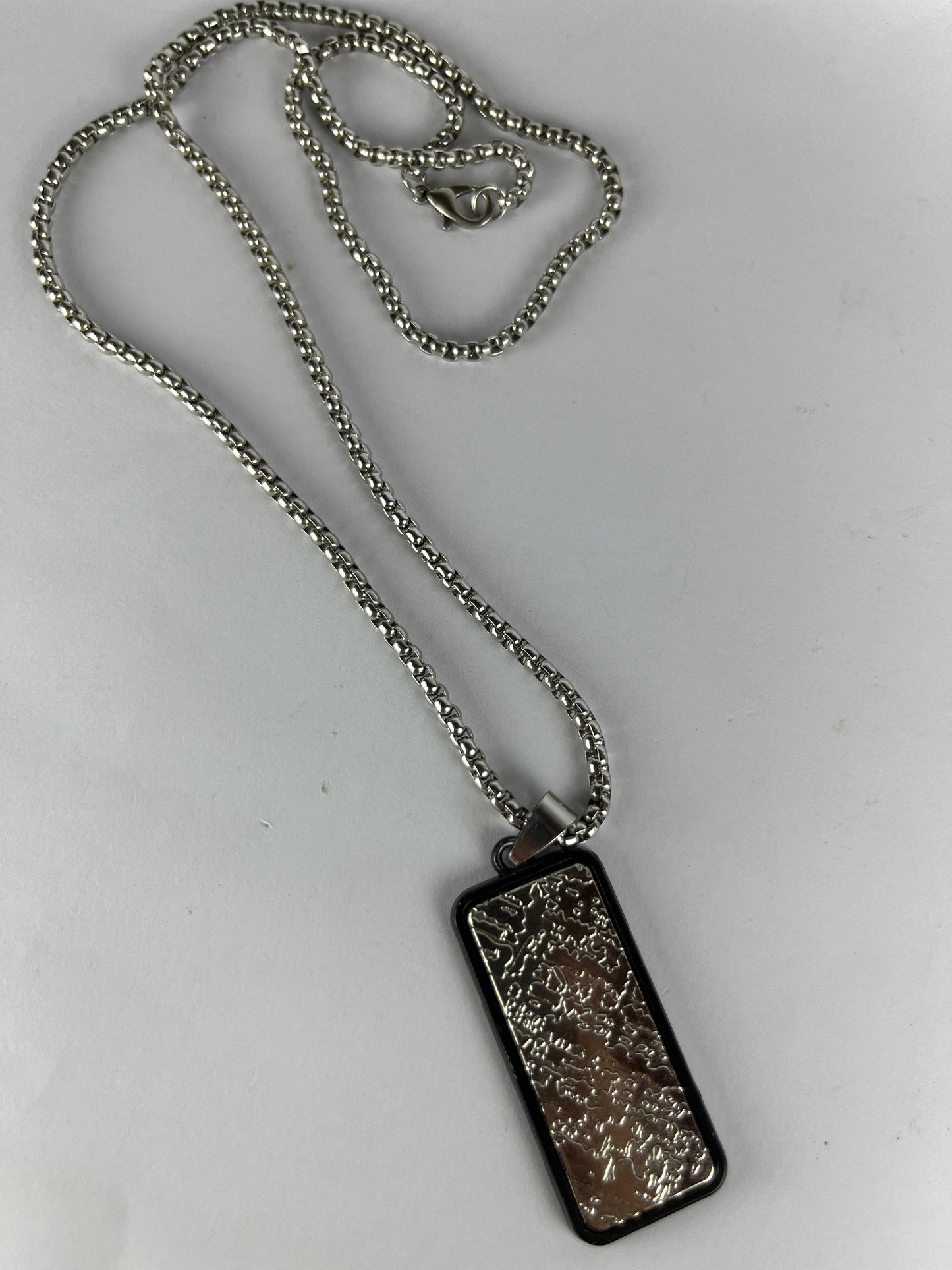 Silver necklace with a rectangular pendant on a white background